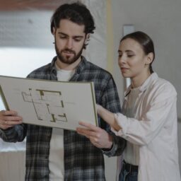 A couple examines a home renovation blueprint indoors, planning improvements together.
