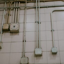 a tiled wall with pipes and a clock on it